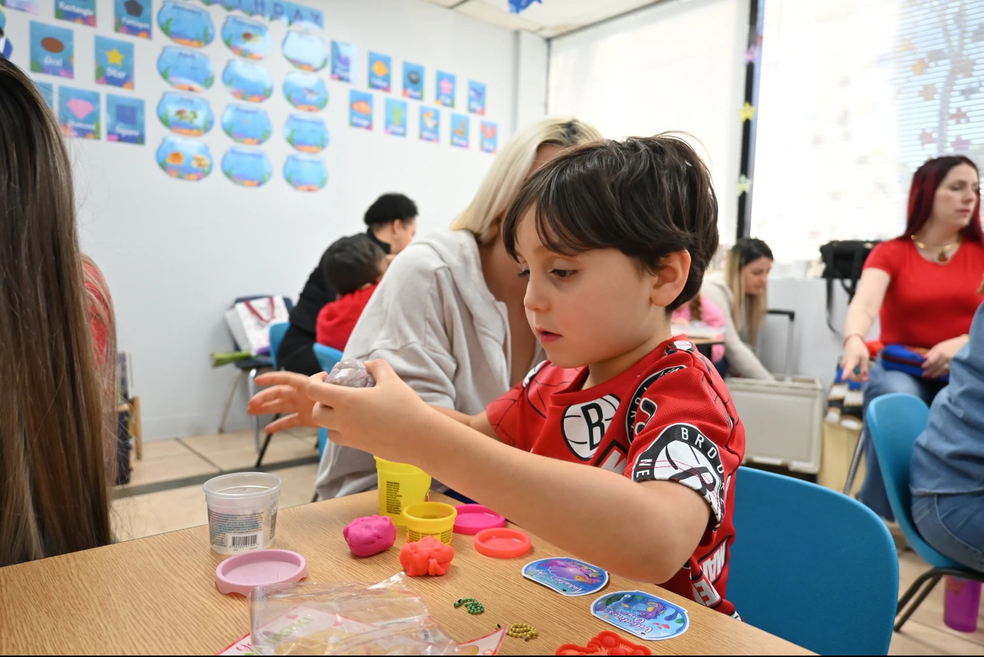 A boy shaping play-dough at a classroom table
