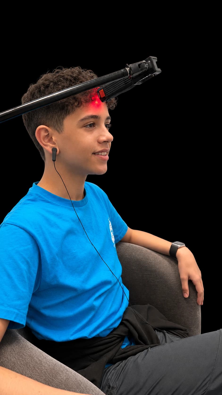 A boy in profile receiving laser stimulation at the forehead